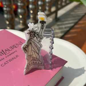 Detailed view of cream acetate Liberty claw clip on pink fashion book background