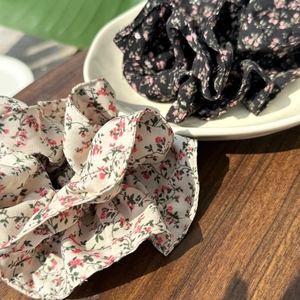 Detail view of two vintage floral scrunchies on a white porcelain plate with soft natural light