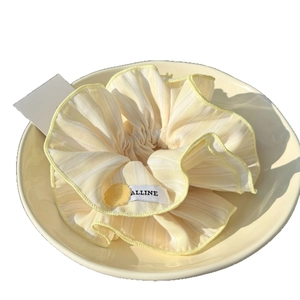 Striped yellow scrunchie with floral button in a ceramic tray for hair styling