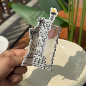 Close-up of Lady Liberty acetate hair claw clip showing fine black line details and yellow torch
