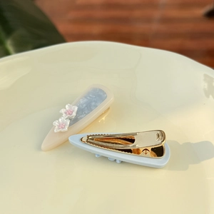 Detailed macro view of marbled blue acetate drop hair clips with small white flower accents