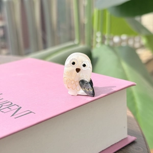 Macro d'une petite barrette hibou en acétate avec finition nacrée et détails dorés brillants