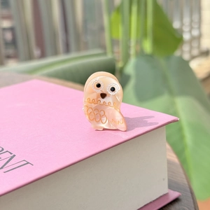 Détail de la pince à cheveux hibou rose en acétate avec finition nacrée et dorée