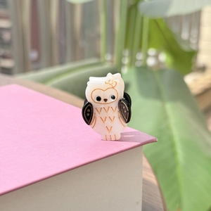 Détail d'une mini pince à cheveux hibou en acétate avec nœud doré et texture perlée