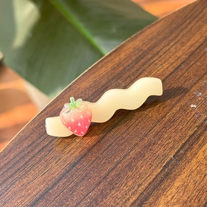 Nahaufnahme einer süßen Erdbeere Wellen-Haarklammer mit rosa Frucht und grünen Blattdetails