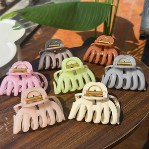 Macro view of octopus-style resin hair claws in assorted macaron colors on a wood table