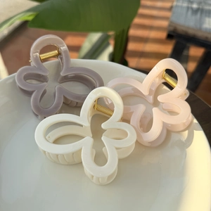 Trois pinces à cheveux fleur en violet pastel, crème et rose dans un bol blanc
