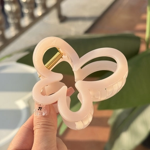 Détail de la pince à cheveux papillon rose clair avec ressort en métal doré