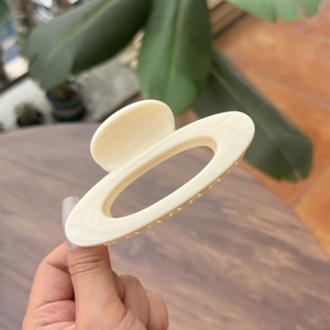 Elegant cream hollow oval hair claw clip with glossy finish for a minimalist summer style