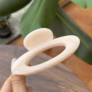 Detailed close-up of cream marble texture hair claw clip with oval hollow design