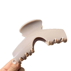 Pince à cheveux mate beige pour cheveux épais tenue en main sur fond blanc