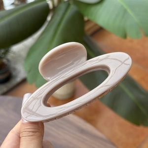 Elegant 10cm hollow oval hair claw in nude beige color with glossy acrylic finish