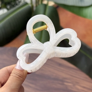 Elegant white translucent bow hair claw clip with heart cutouts and gold spring detail