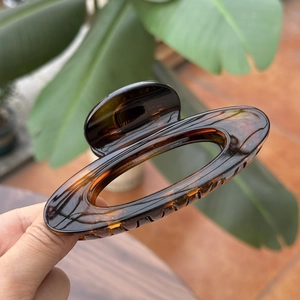 Detail of tortoise shell hair claw clip featuring elegant oval hollow design and glossy finish