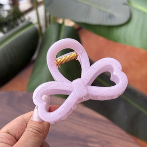 Detail of pink bow hair claw clip with subtle grid pattern and gold metal spring