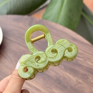 Dettaglio di un elegante fermaglio per capelli verde chiaro con motivo a nuvola