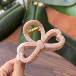 Detail view of pink marble bow hair claw clip with heart cut-outs and golden metal spring