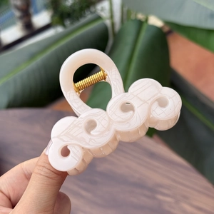 Dettaglio di un elegante fermaglio per capelli da 8 cm color crema effetto marmo