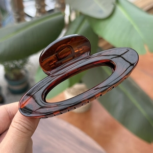 Detail of amber tortoiseshell resin hair claw with hollow oval design and metal spring