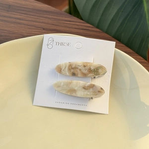Close-up of elegant acetate hair clips with marble texture on a display card