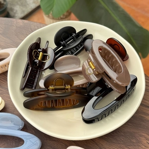 Assorted minimalist 10cm hollow hair claws in neutral colors on a ceramic tray