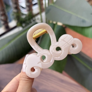 Dettaglio della pinza per capelli beige a forma di nuvola con molla in metallo dorato