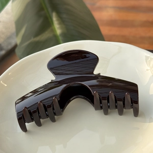 Détail d'une grande pince à cheveux marron foncé brillante dans un plat en céramique