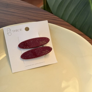 Detail view of oval burgundy glitter hair clips with gold Barrette la France logo