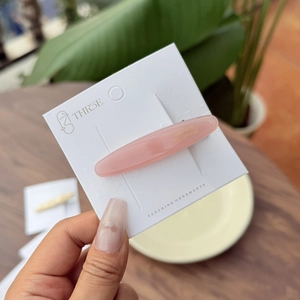 Pink handmade acetate oval hair clip on branding card shown in a lifestyle outdoor setting