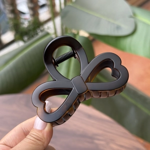 Detail view of 8cm brown tortoiseshell hair claw clip with heart and bow design