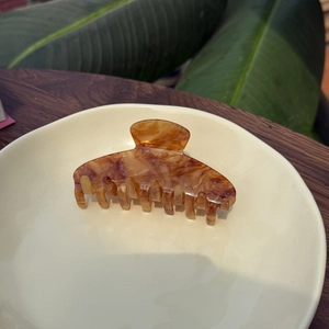 Pince à cheveux classique en acétate écaille d'ambre sur une assiette en céramique beige