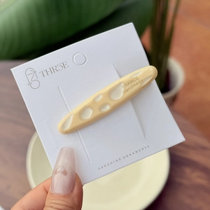 Elegant long oval acetate hair clip in cream with white pattern on brand card