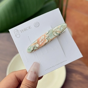 Detail of handmade marble acetate hair clip with golden engraving on display card