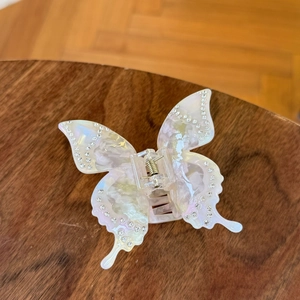 Elegant pearl white acetate butterfly hair claw clip with rhinestones on dark wood