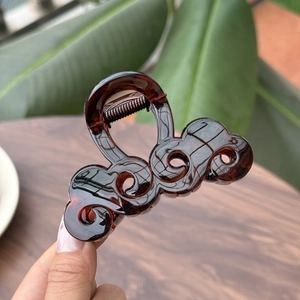 Dettaglio della molletta per capelli tartarugata marrone con design elegante a onde