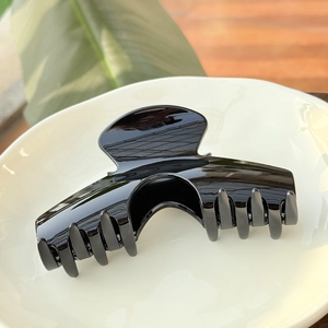 Gros plan d'une grande pince à cheveux arquée noir brillant sur une assiette