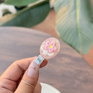 Detail van roze hars bloem haarspeld met geel hart op zilveren metalen eendenbekklem