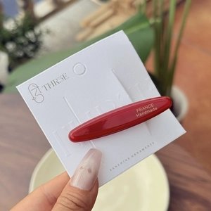 Detail of red acetate oval hair clip with gold label on France Handmade card