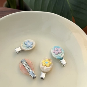 Detail van vier kleurrijke acetaat bloem haarclips met hartjes in een keramieken kom