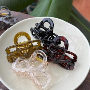 Close-up of assorted resin bow hair claws in a ceramic plate on a wooden desk