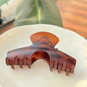 Détail macro d'une grande pince à cheveux ambre écaille sur assiette en céramique