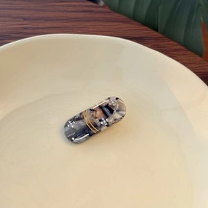 Detail of marble pattern acetate hair clip with rhinestones on a ceramic plate