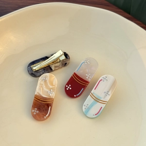 Detailed view of acetic acid capsule hair clips with marble textures and rhinestone accents