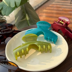 Grandes pinces à cheveux minimalistes vert avocat et rouge vin sur une assiette blanche