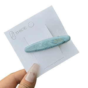 Light blue marble acetate hair clip with gold lettering on white display card