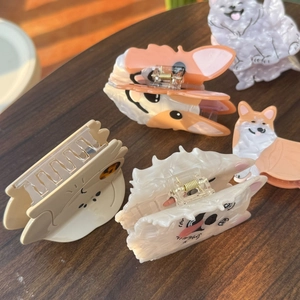 Detailed macro view of four animal-shaped acetate hair claws with premium marble textures