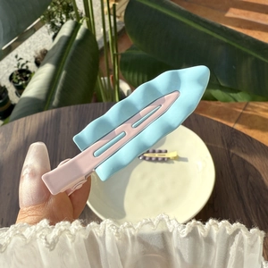 Fermaglio per capelli a onde rosa e blu in mano per un accessorio di stile da donna