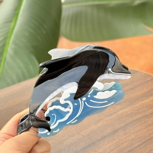 Détail de la pince à cheveux dauphin en acétate avec motif de vague bleue et fini brillant