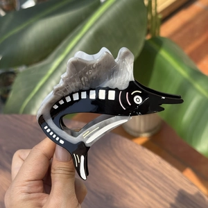 Detailed view of handmade fish-shaped hair claw clip in marble grey and black acetate