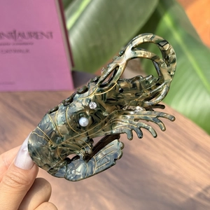 Shrimp shaped acetate hair claw clip with pearl and rhinestone detailing on hand